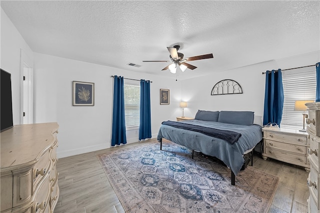 bedroom featuring a textured ceiling, light hardwood / wood-style floors, and ceiling fan