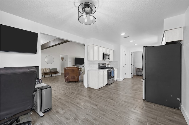 kitchen with backsplash, light hardwood / wood-style floors, a textured ceiling, white cabinets, and appliances with stainless steel finishes