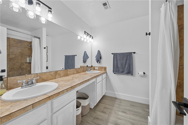 bathroom featuring vanity, wood-type flooring, a textured ceiling, and walk in shower