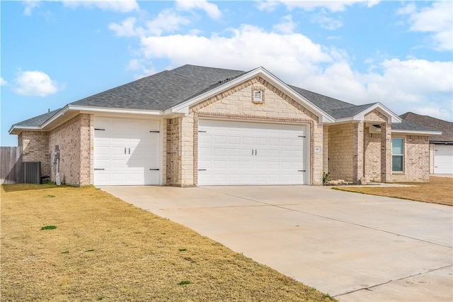 ranch-style house with a garage, a front yard, and central AC unit