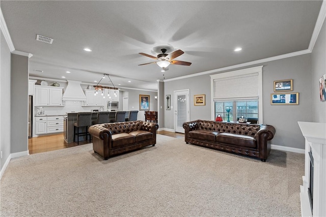 carpeted living room with a textured ceiling, ceiling fan, and ornamental molding