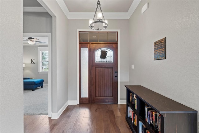 foyer entrance with ceiling fan with notable chandelier, dark hardwood / wood-style flooring, and ornamental molding