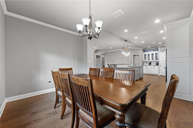 dining area with hardwood / wood-style floors, ceiling fan with notable chandelier, and ornamental molding