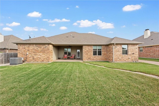 rear view of property featuring a lawn, ceiling fan, cooling unit, and a patio area