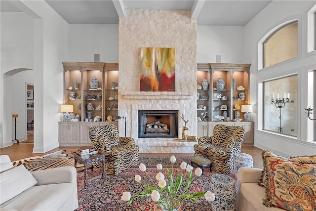 living room featuring light hardwood / wood-style floors, a large fireplace, a healthy amount of sunlight, and a high ceiling