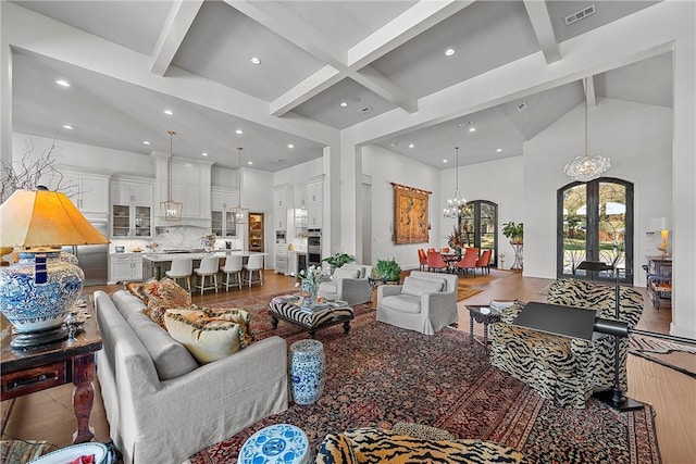 living room with french doors, hardwood / wood-style flooring, high vaulted ceiling, an inviting chandelier, and beamed ceiling