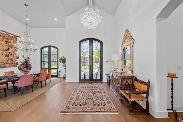 foyer featuring a chandelier, french doors, high vaulted ceiling, and wood-type flooring