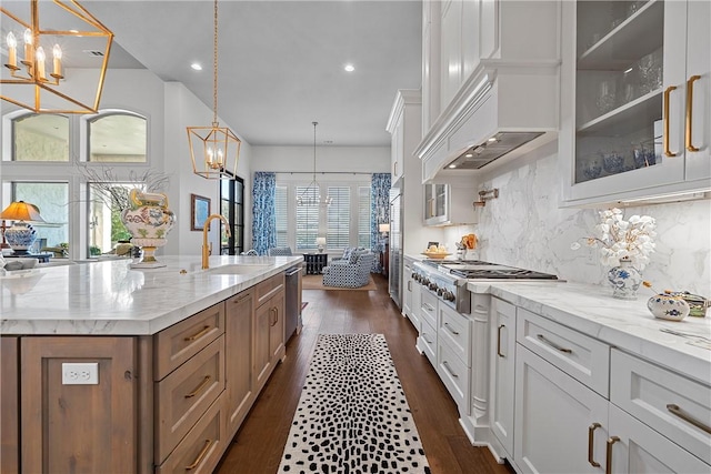 kitchen featuring dark wood-type flooring, sink, decorative light fixtures, white cabinetry, and an island with sink