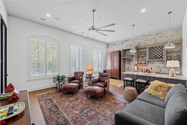 living room featuring dark hardwood / wood-style floors, bar, and ceiling fan