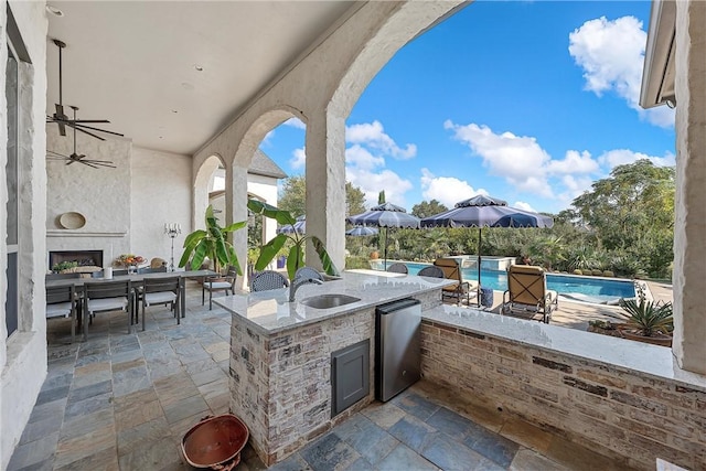 view of patio with exterior fireplace, an outdoor wet bar, and exterior kitchen