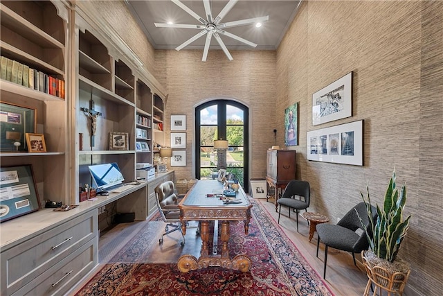 office space featuring french doors, a towering ceiling, built in desk, and ornamental molding