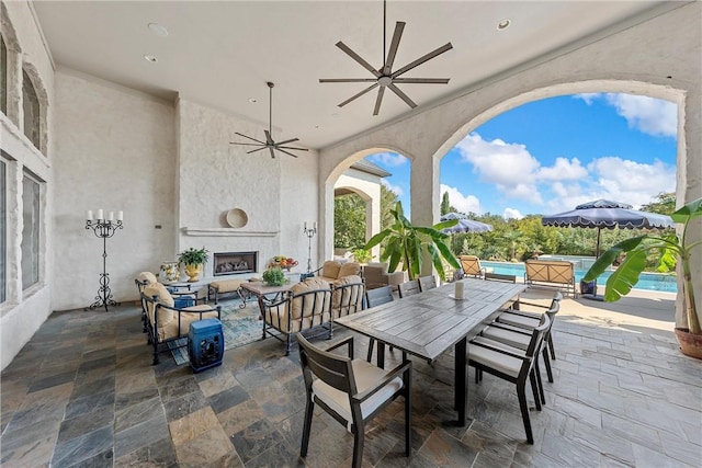 view of patio featuring an outdoor living space with a fireplace, ceiling fan, and a hot tub