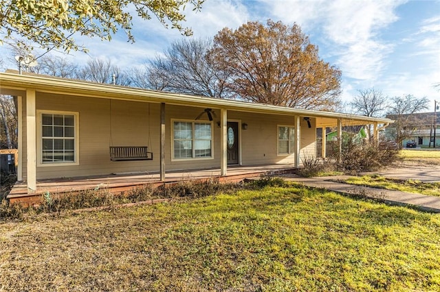 ranch-style home featuring covered porch and a front yard