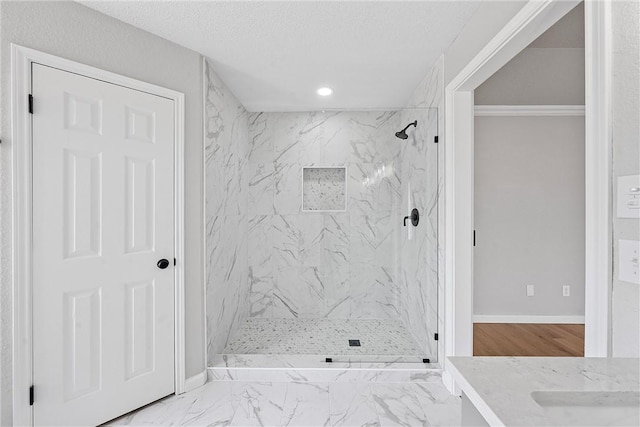 bathroom featuring a textured ceiling, vanity, and tiled shower