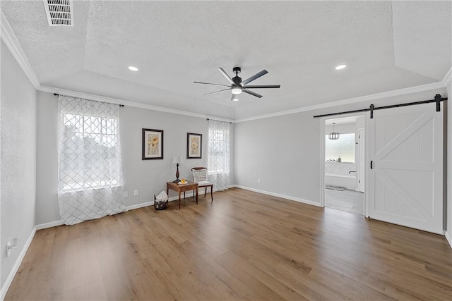 spare room featuring crown molding, hardwood / wood-style flooring, ceiling fan, a barn door, and a textured ceiling