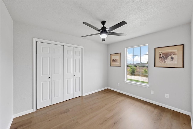 unfurnished bedroom with a textured ceiling, a closet, ceiling fan, and light hardwood / wood-style floors