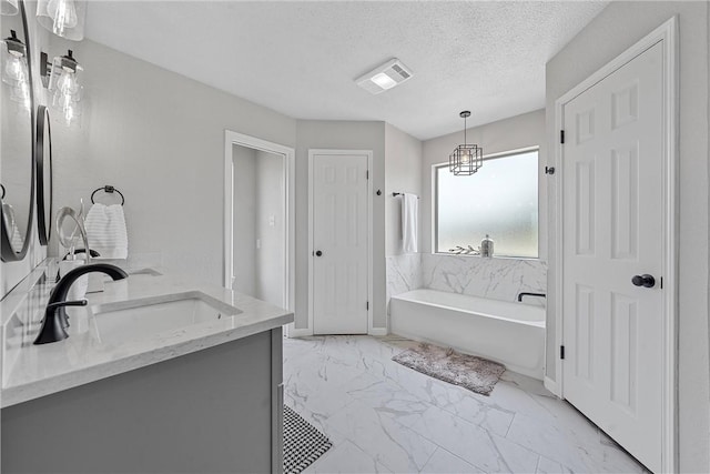 bathroom with a washtub, vanity, a textured ceiling, and a notable chandelier