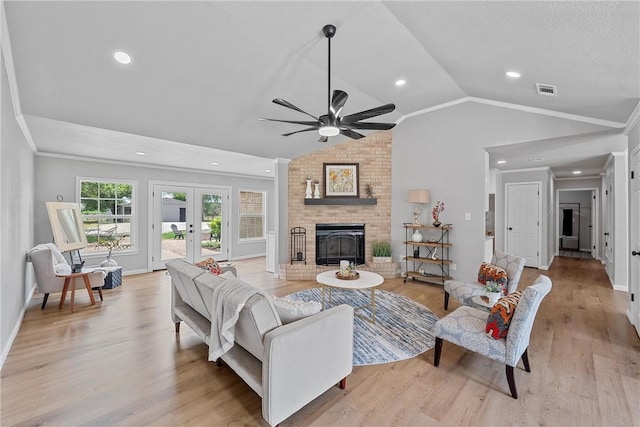 living room with ornamental molding, vaulted ceiling, ceiling fan, light hardwood / wood-style flooring, and a fireplace