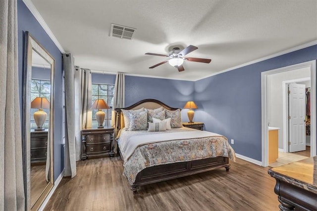 bedroom with a textured ceiling, ornamental molding, hardwood / wood-style flooring, and ceiling fan