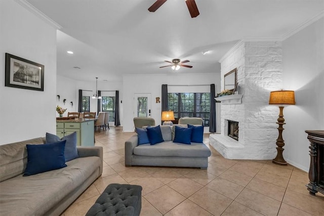 tiled living room with ceiling fan, crown molding, and a stone fireplace