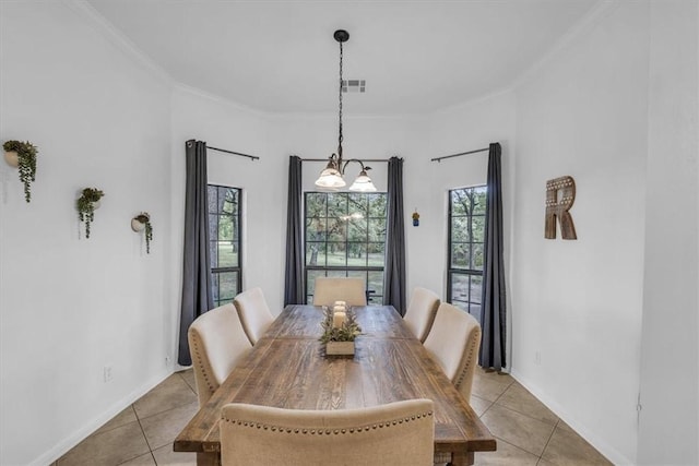 tiled dining space featuring crown molding and a notable chandelier