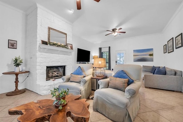 living room with light tile patterned floors, ceiling fan, ornamental molding, and a fireplace