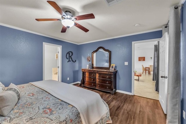 bedroom featuring ceiling fan, ensuite bath, dark wood-type flooring, and ornamental molding