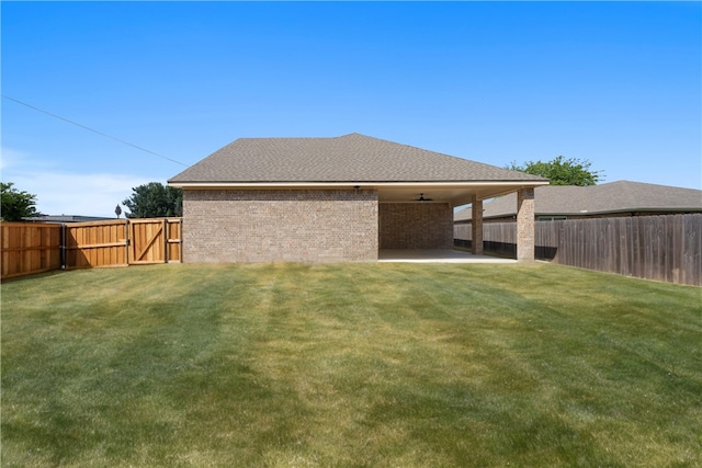 back of property with ceiling fan, a yard, and a patio