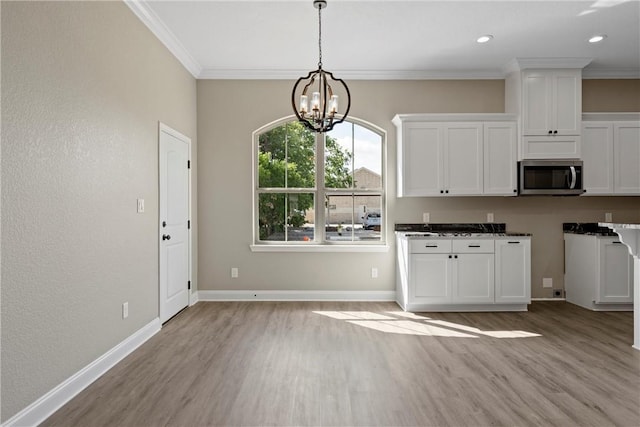 kitchen featuring white cabinets, light hardwood / wood-style floors, crown molding, and a notable chandelier