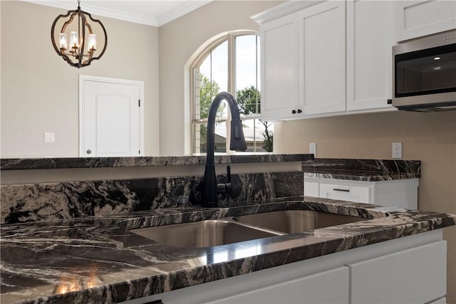 kitchen featuring crown molding, sink, decorative light fixtures, a chandelier, and white cabinetry