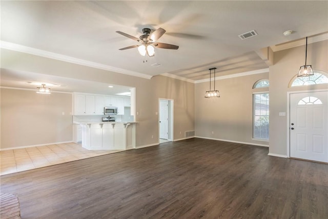 unfurnished living room featuring ceiling fan, hardwood / wood-style floors, and ornamental molding