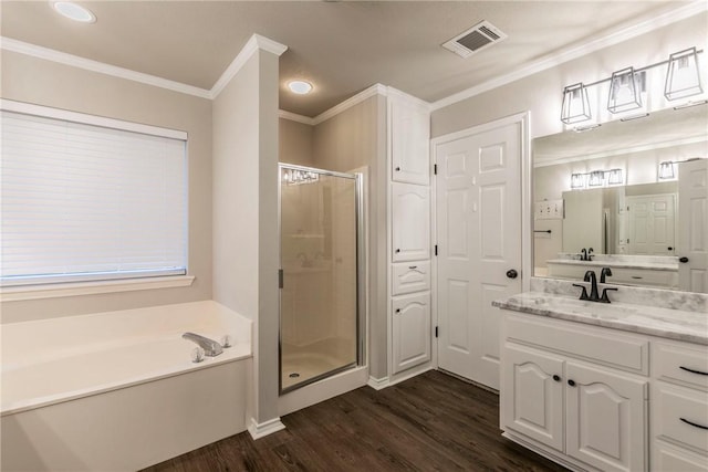 bathroom with plus walk in shower, hardwood / wood-style floors, vanity, and crown molding