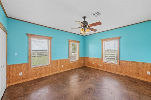 empty room featuring crown molding, ceiling fan, and a healthy amount of sunlight