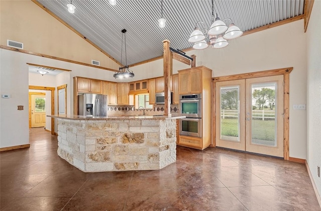 kitchen featuring tasteful backsplash, stainless steel appliances, hanging light fixtures, and a high ceiling