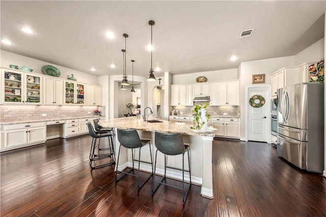 kitchen featuring visible vents, a breakfast bar, stainless steel appliances, white cabinets, and under cabinet range hood