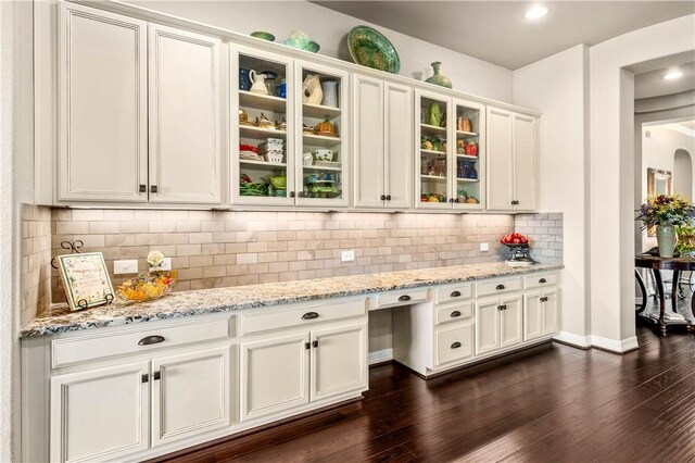 kitchen with dark wood finished floors, light stone counters, tasteful backsplash, and white cabinetry