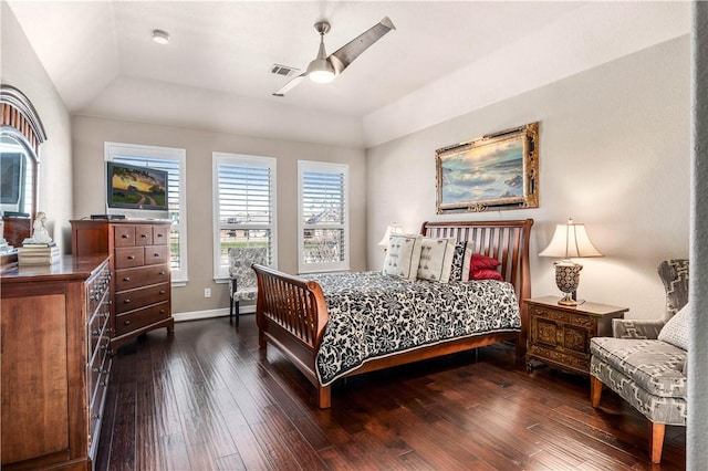 bedroom featuring visible vents, baseboards, a tray ceiling, a ceiling fan, and dark wood-style flooring