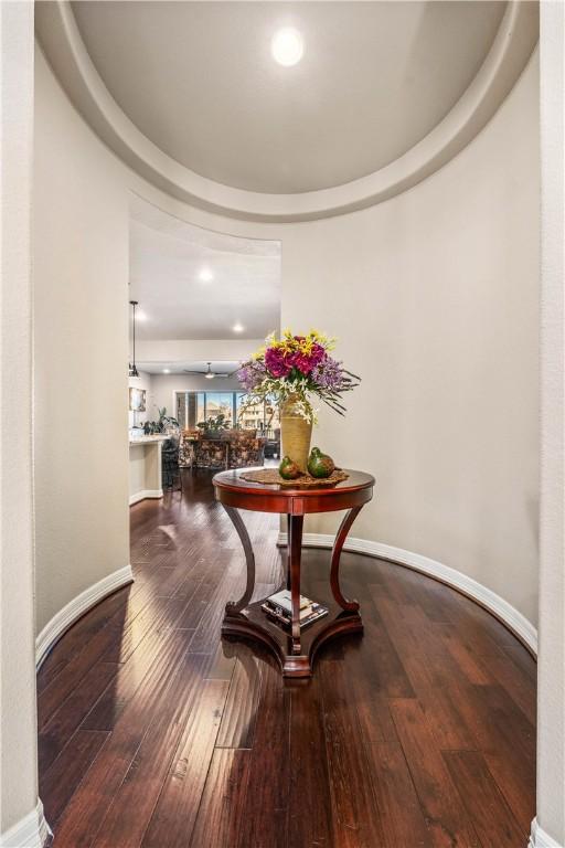 hallway featuring a tray ceiling, baseboards, and wood finished floors