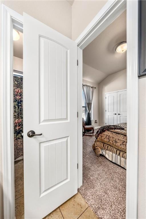 bedroom featuring light tile patterned floors, light colored carpet, and lofted ceiling