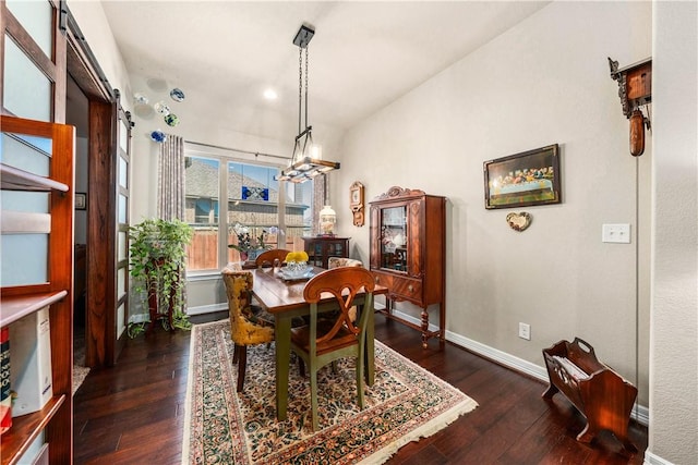 dining area featuring dark wood finished floors, an inviting chandelier, lofted ceiling, and baseboards