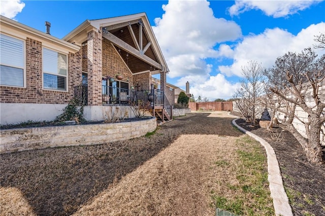 view of property exterior featuring brick siding and fence