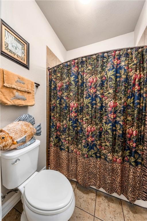 full bath featuring tile patterned flooring, toilet, and a shower with shower curtain