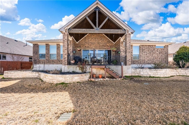 rear view of house featuring stairway, brick siding, and fence