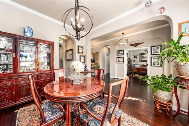 dining space featuring arched walkways, ornamental molding, an inviting chandelier, and hardwood / wood-style floors