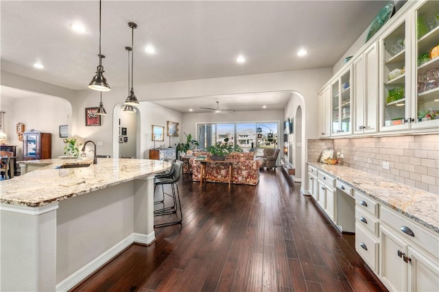 kitchen with a sink, arched walkways, dark wood-type flooring, and open floor plan