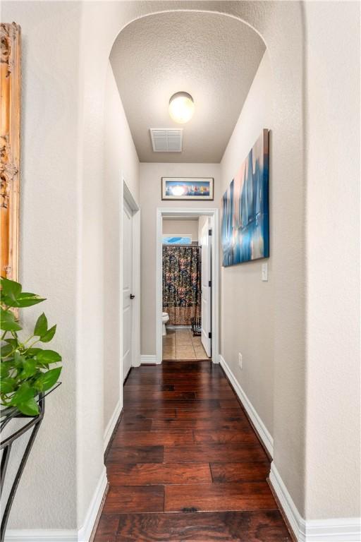 hall with visible vents, baseboards, and wood finished floors