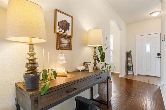 entryway with baseboards, arched walkways, and hardwood / wood-style floors