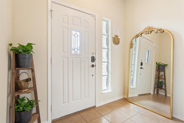 foyer entrance with arched walkways, light tile patterned flooring, and baseboards