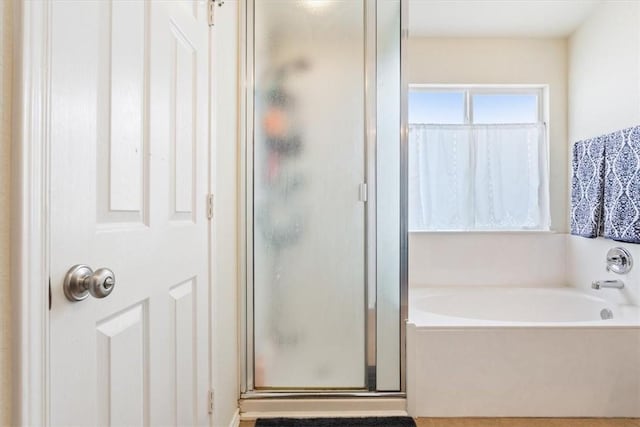 bathroom featuring a shower stall and a bath