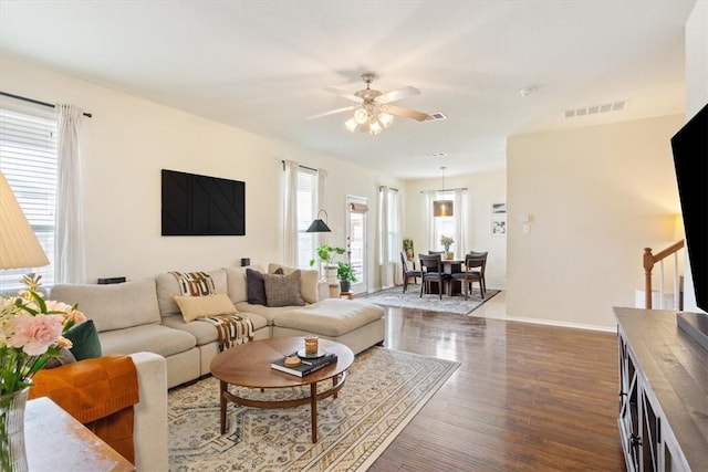 living area featuring visible vents, ceiling fan, wood finished floors, baseboards, and stairs